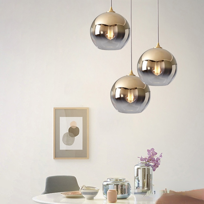 Three gold-gradient glass globe pendants above a dining table at different heights