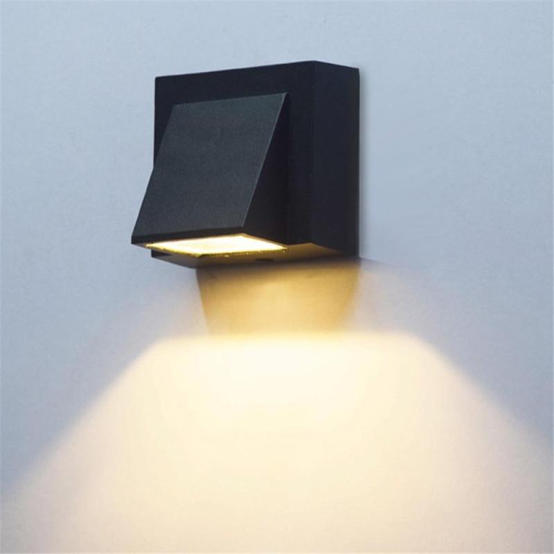 Black single-head Orr wall lamp lighting a pale wall below