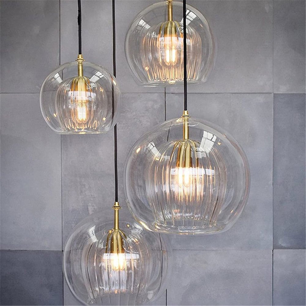 Four clear globe pendants staggered against a gray tiled wall