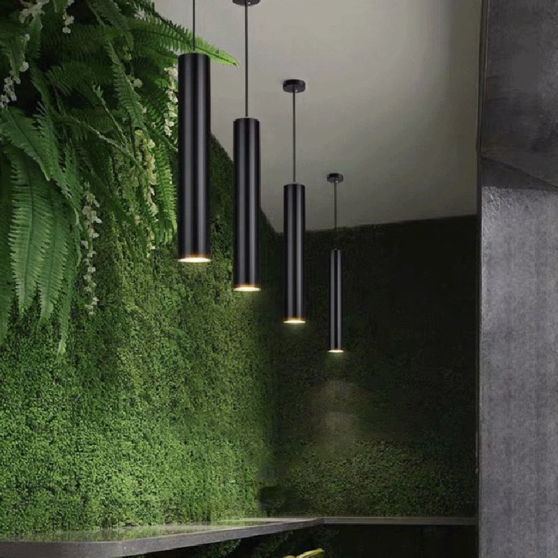 Several black Edge tube pendants beside a green feature wall.