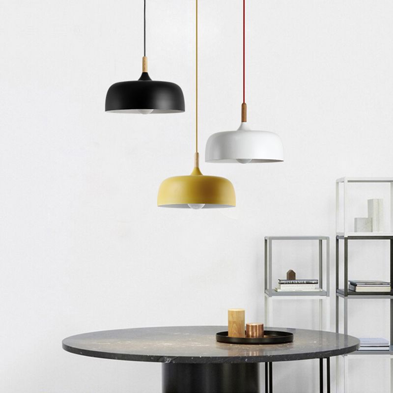 Black, white and yellow dome pendants above a dark round table and open display shelves
