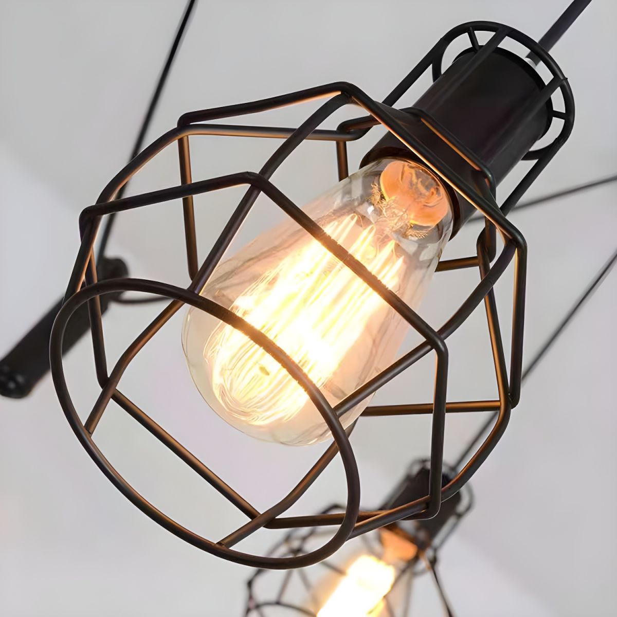 Close view of glowing filament-style bulb inside an Alessio wire cage
