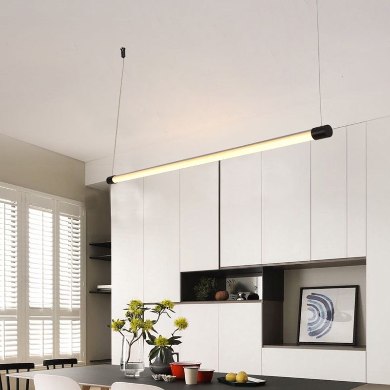 Black-endcap linear pendant above a home table with flowers, fruit and white kitchen cabinets