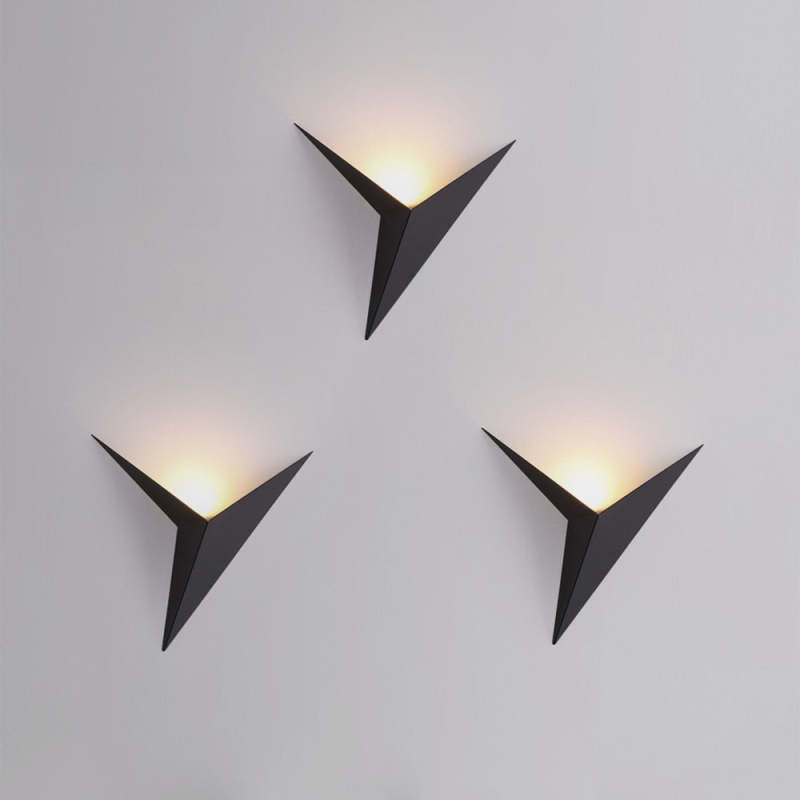 Three black Orr triangular wall lamps casting light upward