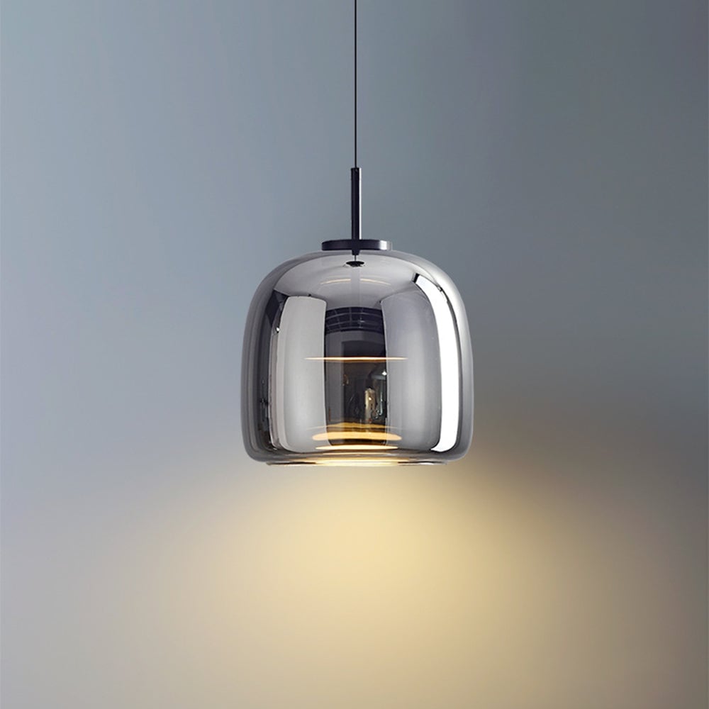 Close view of tall smoky-gray Hailie glass shade with dark central housing and warm-looking glow against gray wall