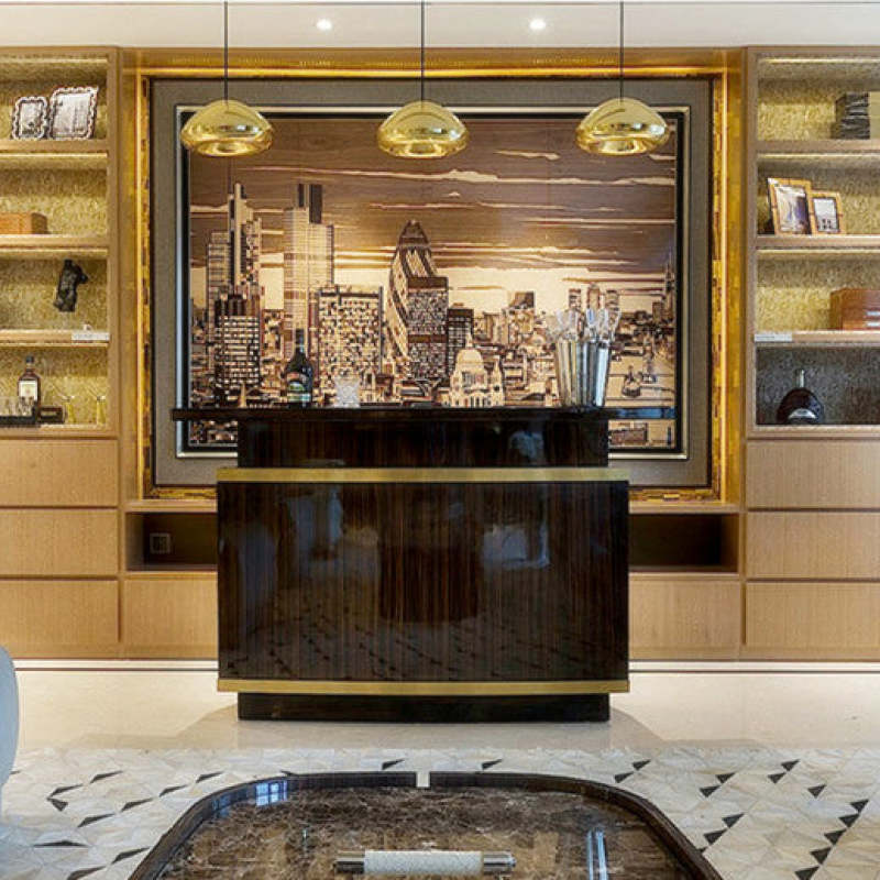 Three gold reflective dome pendants above a black cabinet and framed city artwork