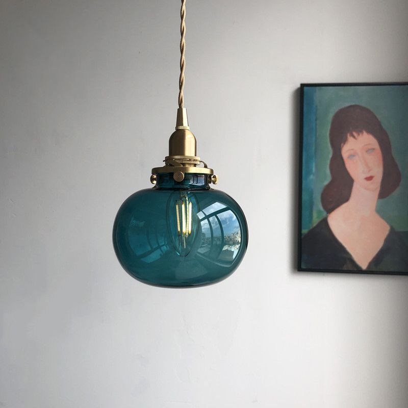 Blue glass globe pendant beside portrait wall art