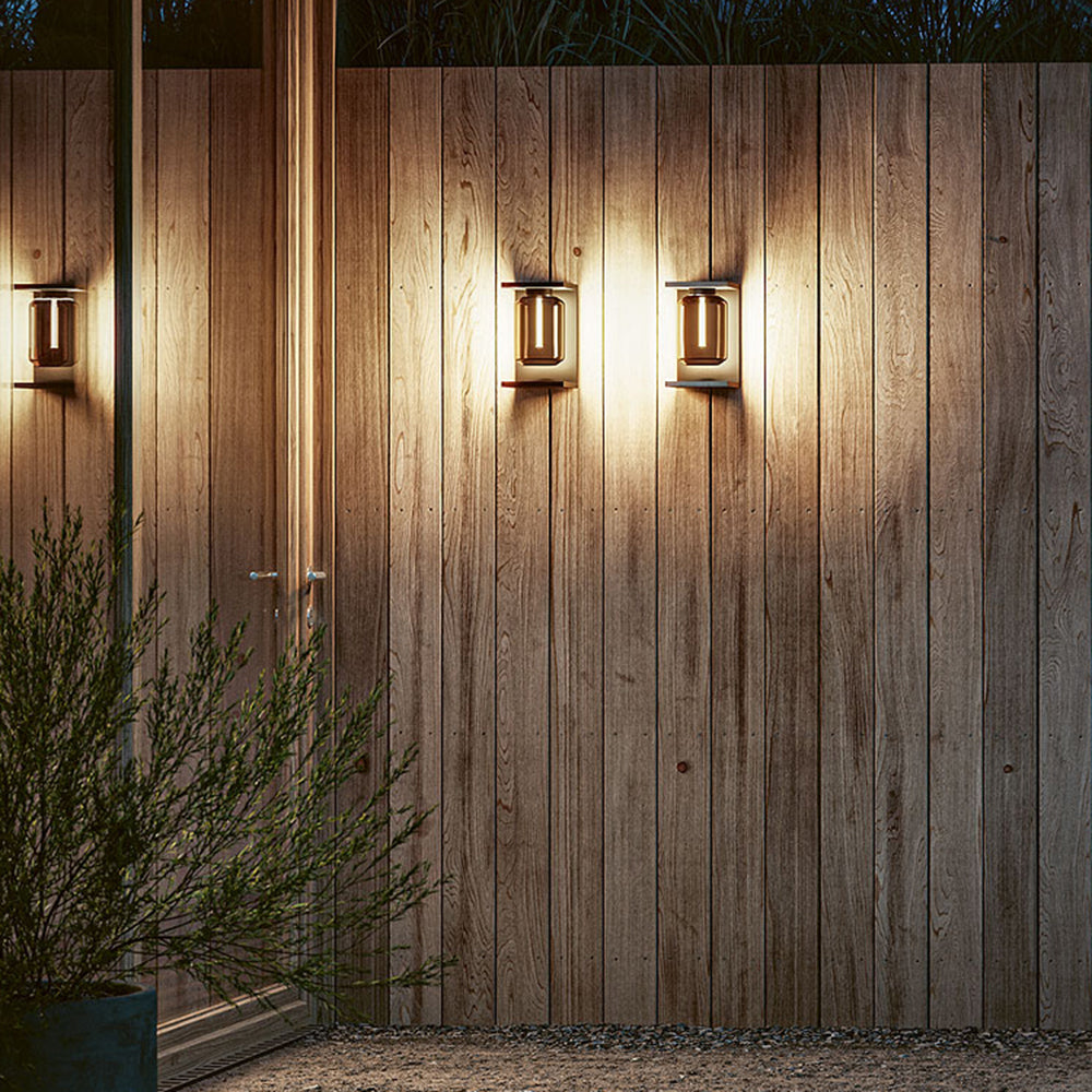 Three illuminated Orr lanterns along a wooden outdoor wall.