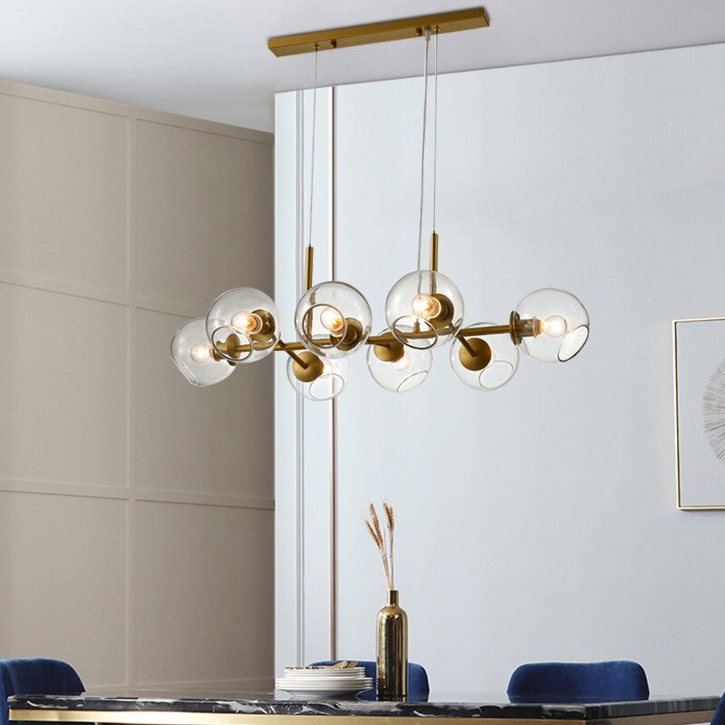 Gold Valentina clear-globe pendant with rectangular canopy above a dark dining table and blue chairs