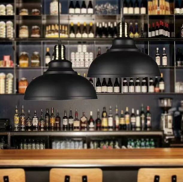 Two black dome pendants with metallic upper collars above a bar and shelves of bottles