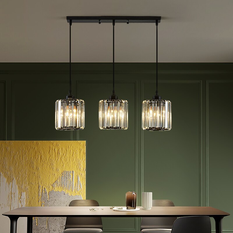 Three black Herbert cylindrical glass shades above a long dining table against a green wall and yellow artwork