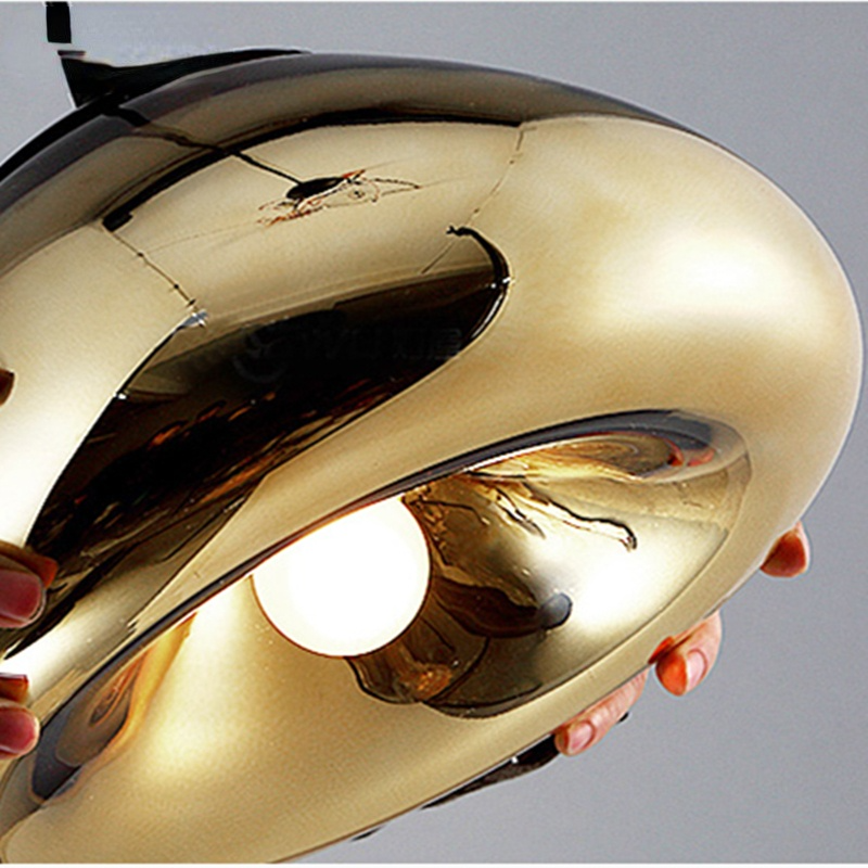 Hands holding the underside of a gold reflective shade with a lit white bulb