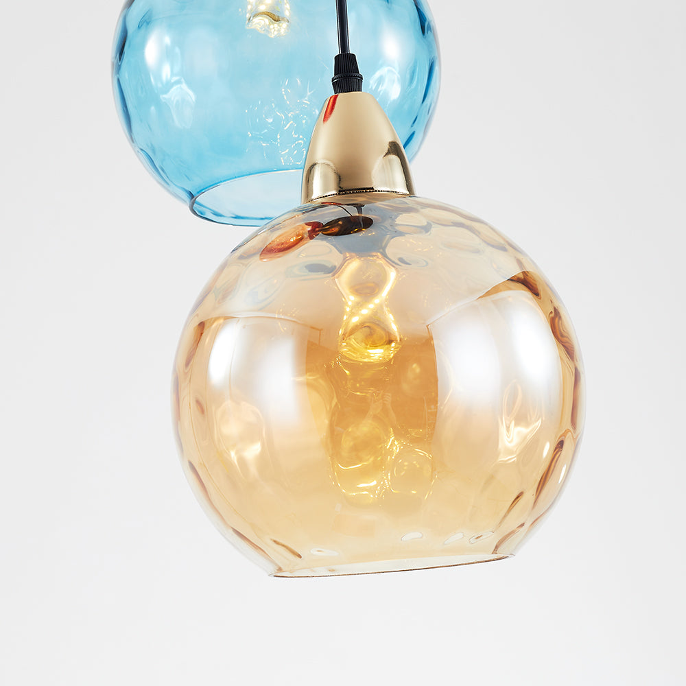 Close-up of an amber rippled glass globe with an open bottom and a blue globe behind