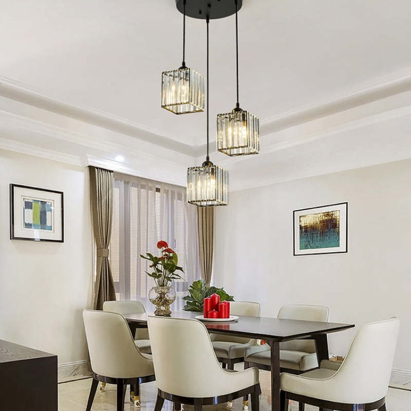 Black three-square-shade cluster from one round canopy above dark dining table, white chairs, red candles and flowers