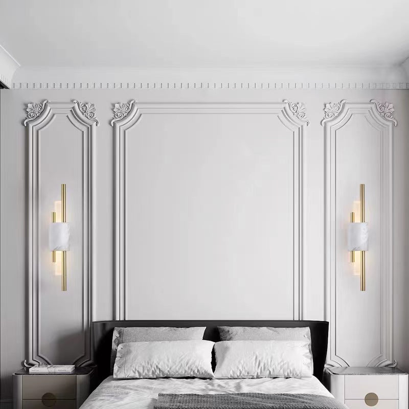 Two white-veined Alana wall lights flanking a bed against an ornate white panelled wall