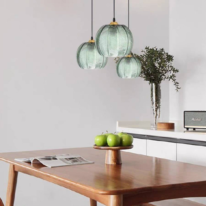 Three green glass pendants arranged above a wooden dining table.