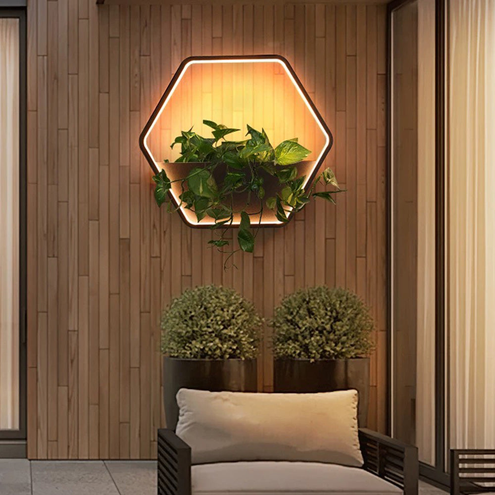 Orr hexagonal shelf light with greenery above an outdoor sofa against wood cladding.