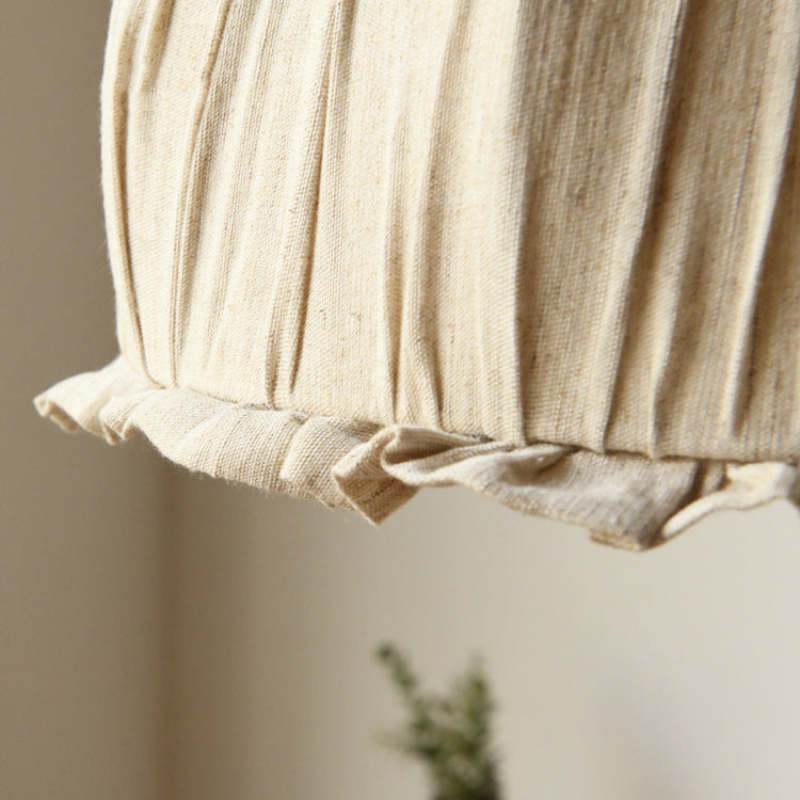 Close-up of the ruffled fabric edge and gathered folds at the bottom of the pendant shade