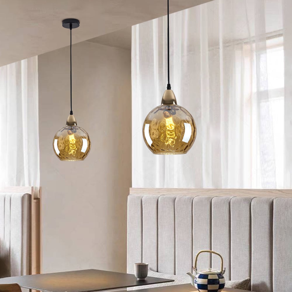 Amber-toned rippled glass pendants above a banquette with black ceiling plate