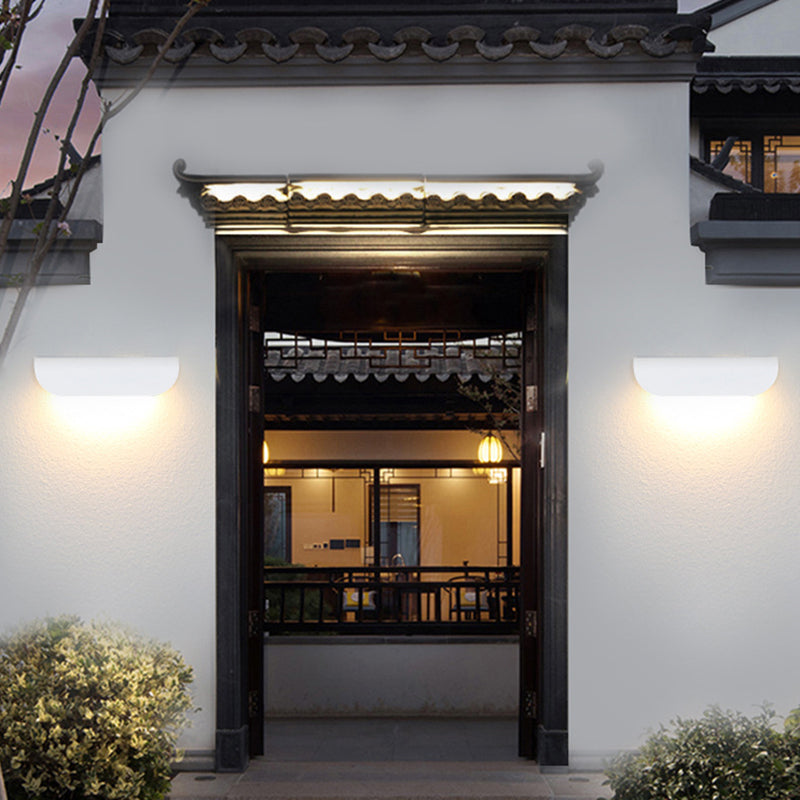 Two white curved wall lights flanking a courtyard entrance beneath a tiled roof