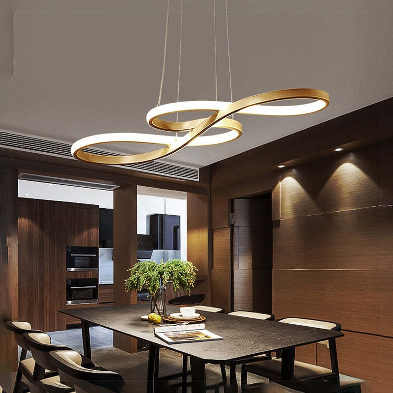 Gold crossing-loop pendant above a dark dining table
