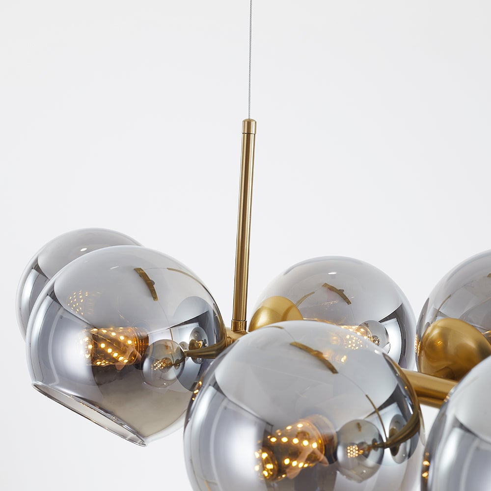 Close gold suspension sleeve and horizontal bar among darker reflective glass globes with glowing bulbs