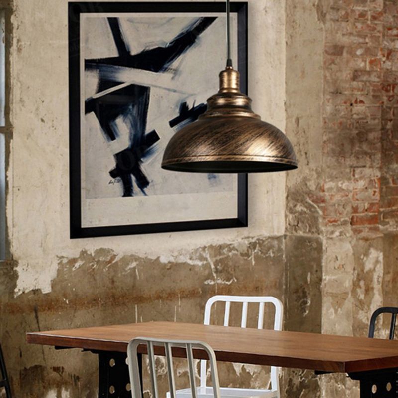 Copper-tone stepped dome pendant in a dining setting with wooden table, metal chairs and aged plaster wall