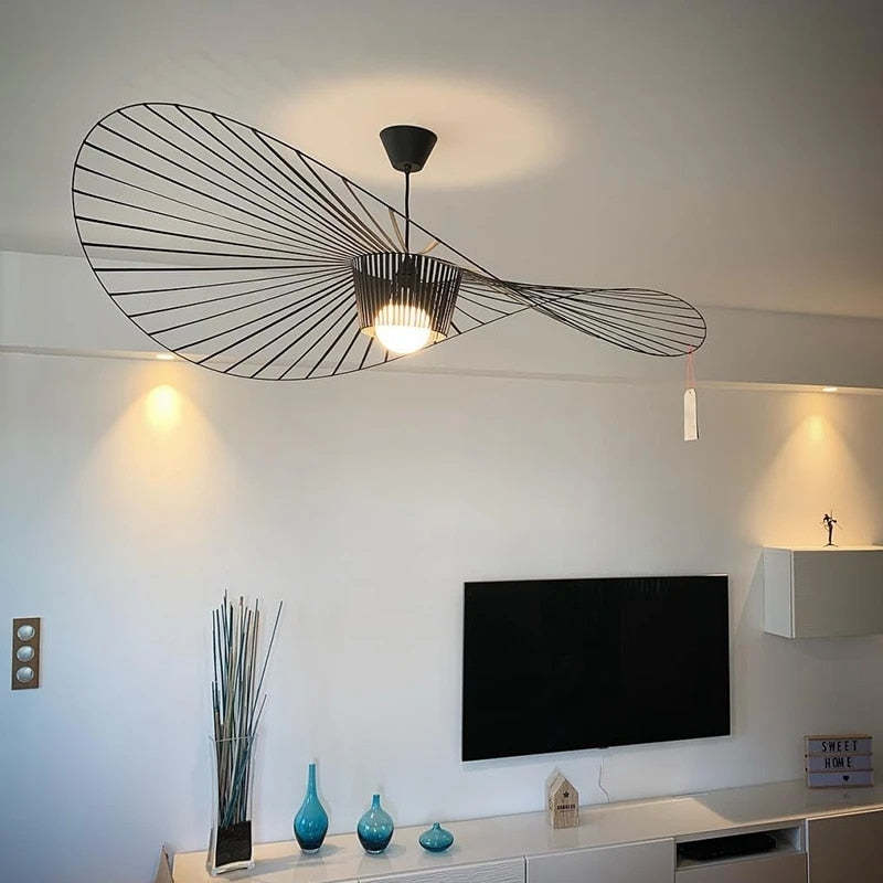 Black wavy radial-line pendant with a lit central bulb surround above a TV and white media cabinet