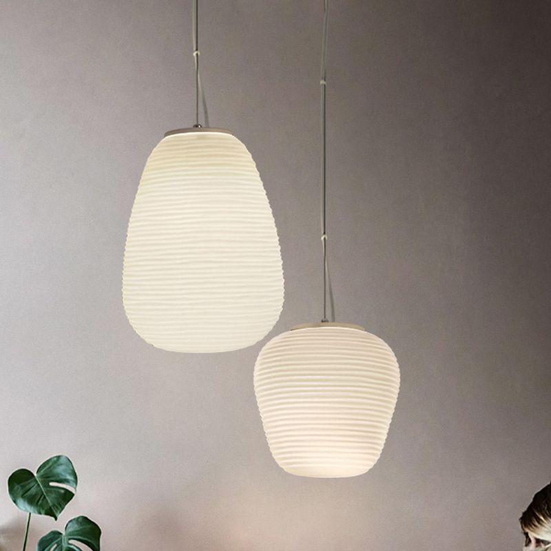 Tall and compact white ribbed pendants lit at different heights beside foliage