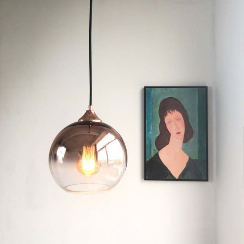 Rose-gold gradient glass globe pendant beside a framed portrait
