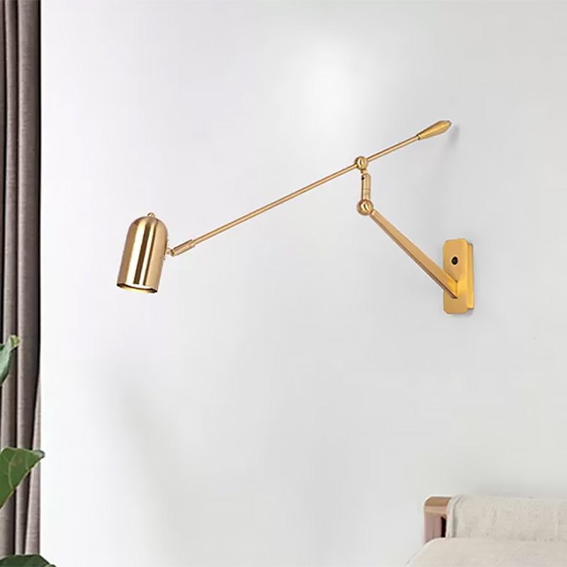Freja gold wall lamp with its long arm angled upward above a sofa.