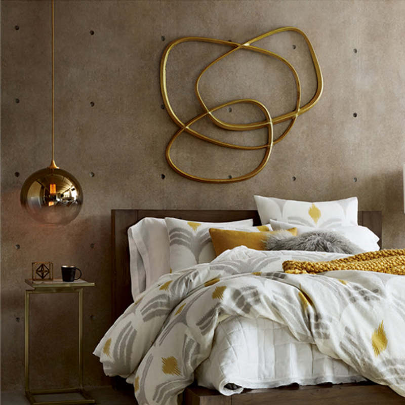 Gold-gradient globe pendant above a bedside table next to a bed
