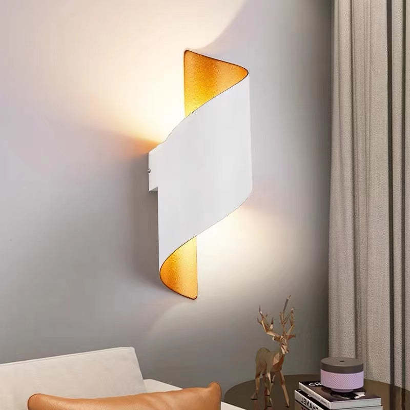 White wall light with gold-tone interior beside a chair, curtains and a book-topped side table