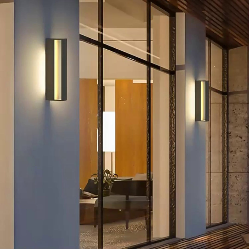 Black open-frame wall lights glowing beside large glazed doors under a wooden overhang