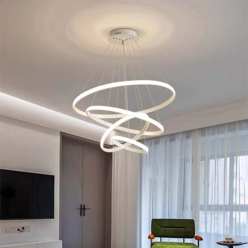 White four-ring pendant light in a tilted cascade above a bedroom with wardrobe, television and Green chair