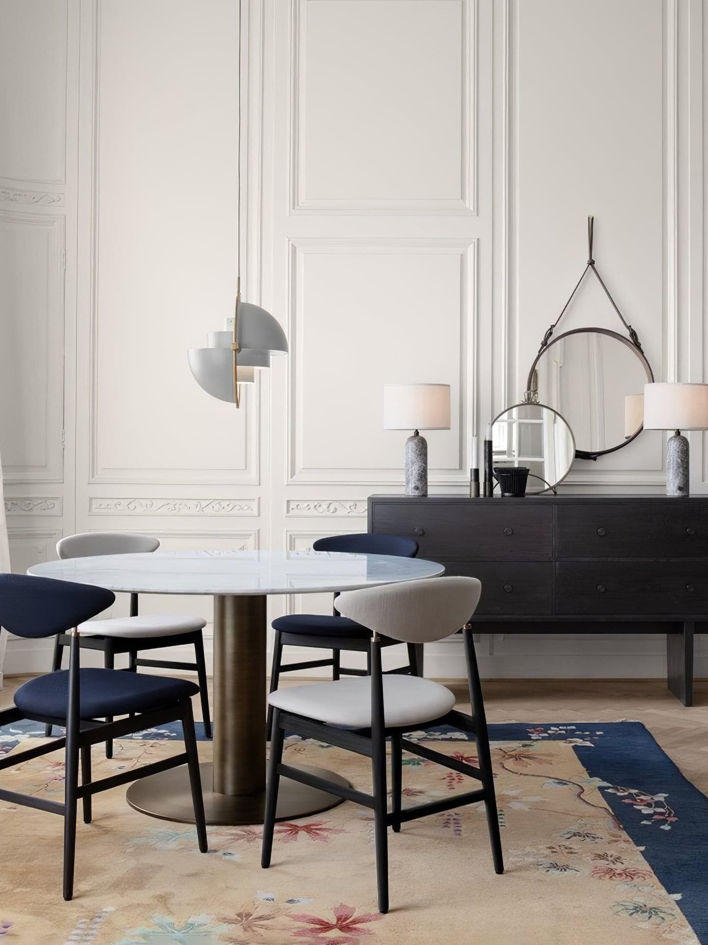White pendant with open shade halves beside a dining table