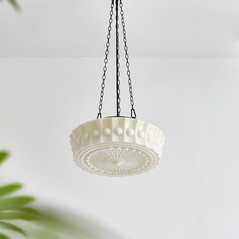 Pale glass pendant and black chains near foliage