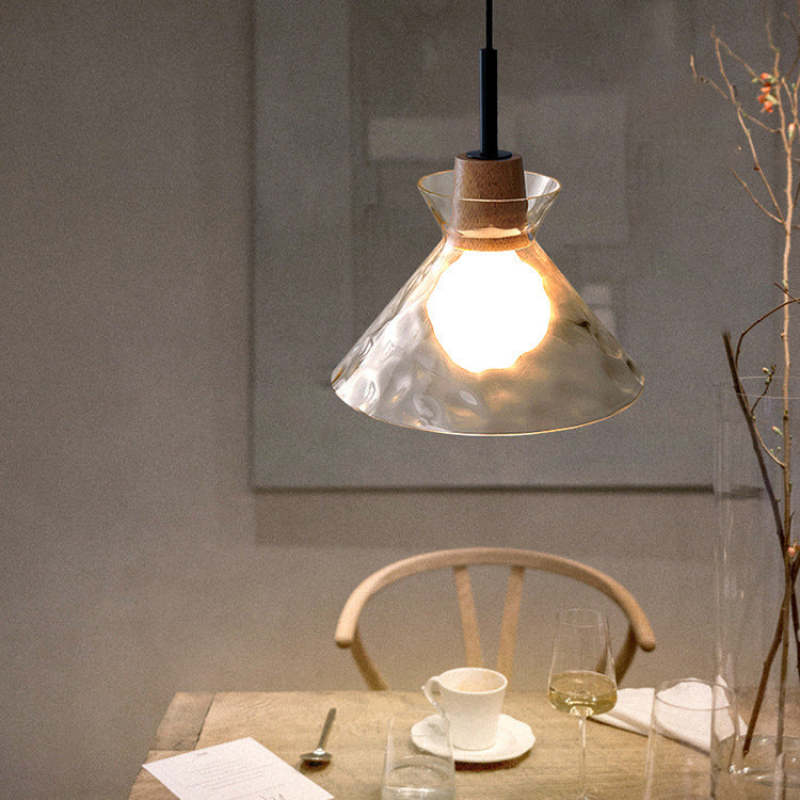 Single conical glass pendant beside chair and table