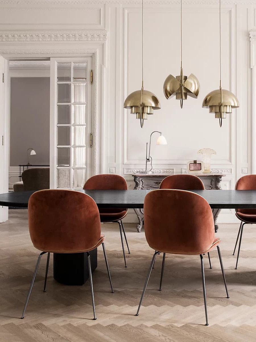 Three copper-finish pendants above a black dining table