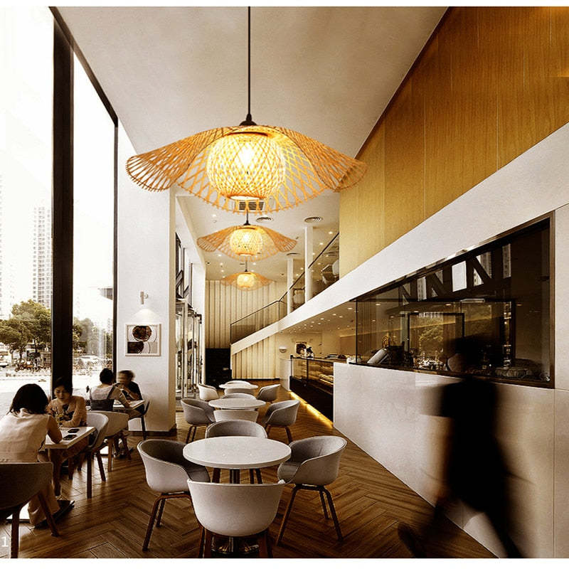 Basket-centred woven pendants above pale round tables and grey chairs beside tall windows