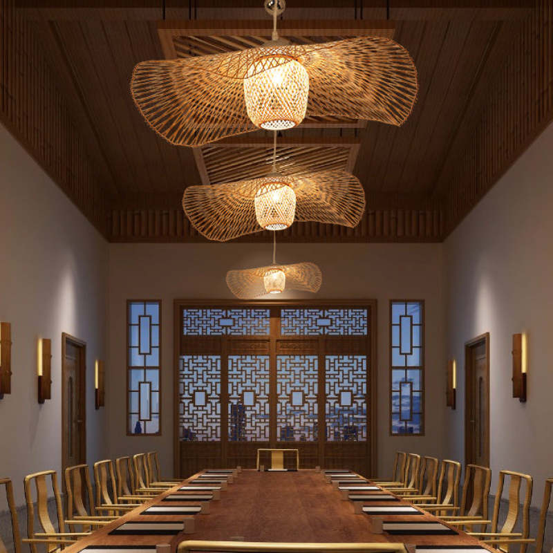 Three woven pendants along a long wood dining table beneath a paneled ceiling