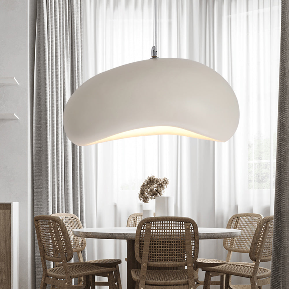 White Byers bread-shaped pendant light above a round table with woven chairs, dried flowers and sheer curtains behind.