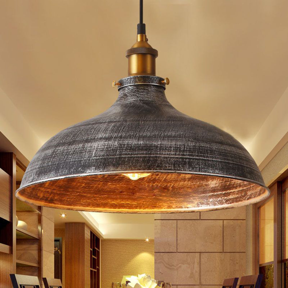 Close view of an illuminated Alessio distressed metal bowl shade and gold-coloured fitting.