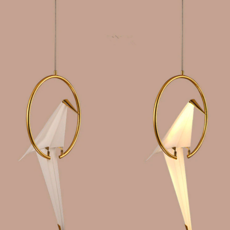 Two separate single-bird pendants against a pink wall, one lit and one unlit.