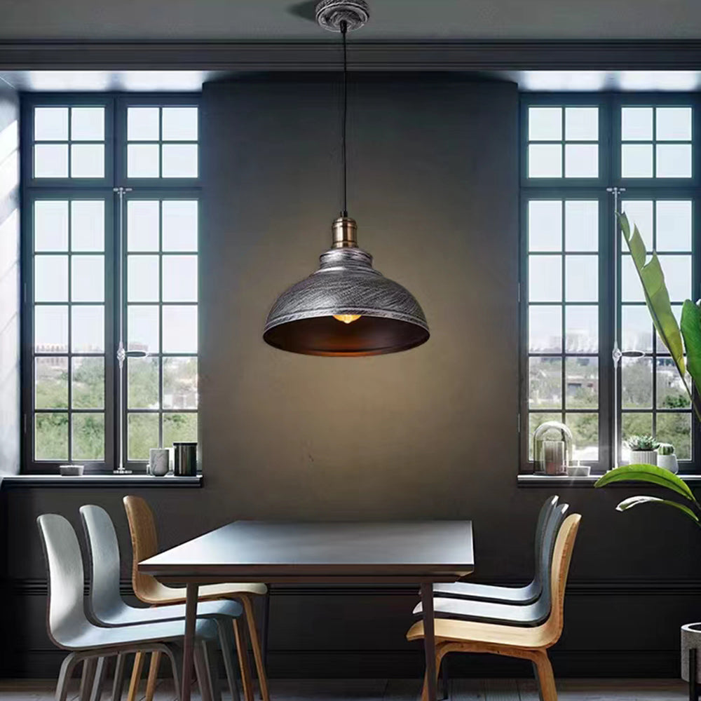 Alessio distressed bowl pendant above a dining table beside large windows.