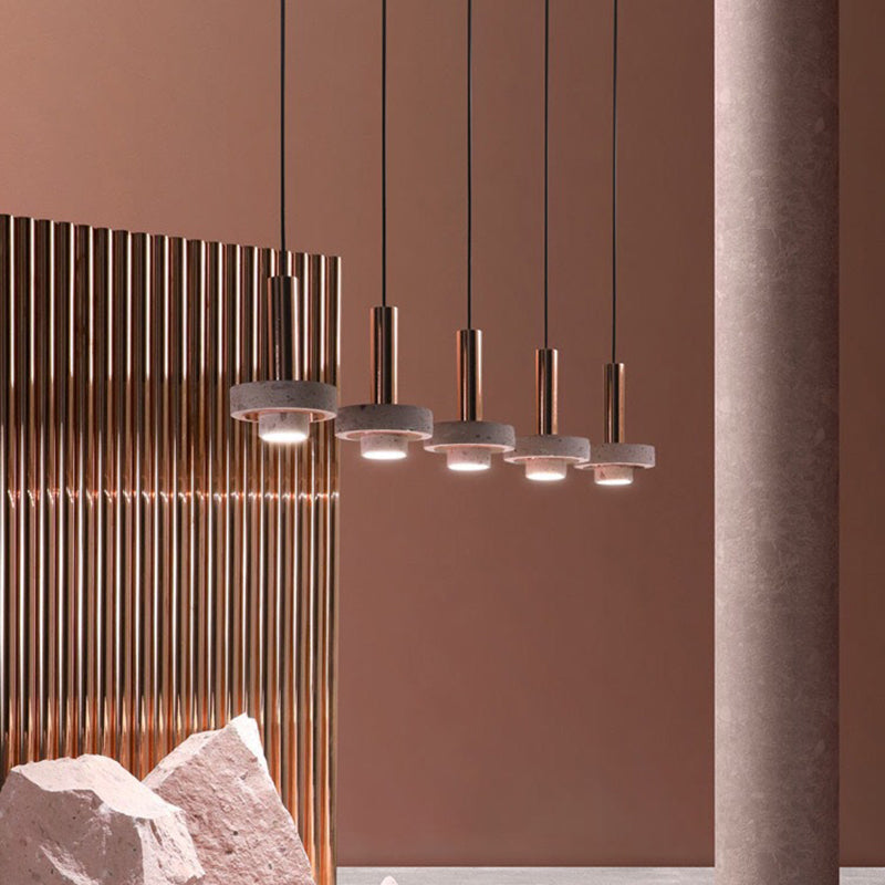 Five separately hung speckled disc pendants in a row before reflective metal columns and a reddish wall