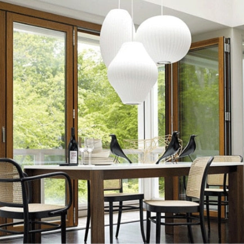 Grouped ribbed white pendants over table by window