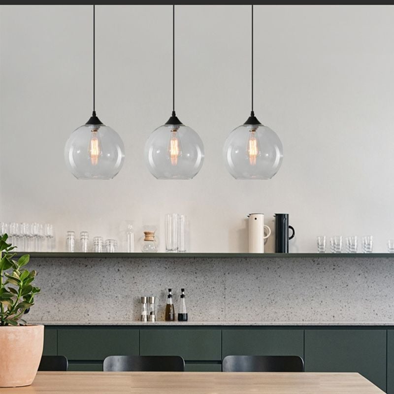 Three Clear glass globe pendants arranged above a kitchen counter