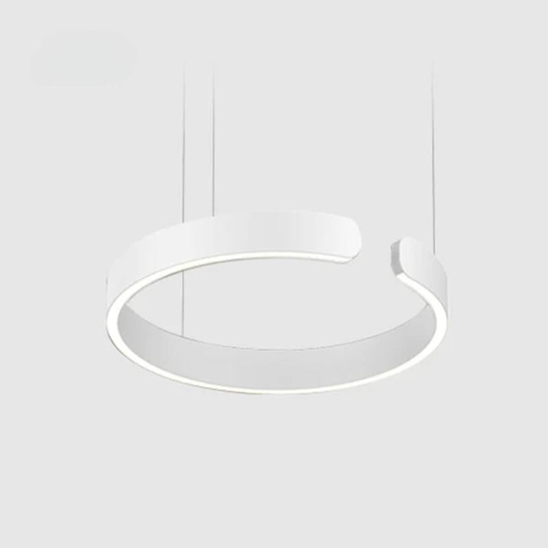 White ring pendant with a gap between its rounded ends and bottom lighting on a pale background