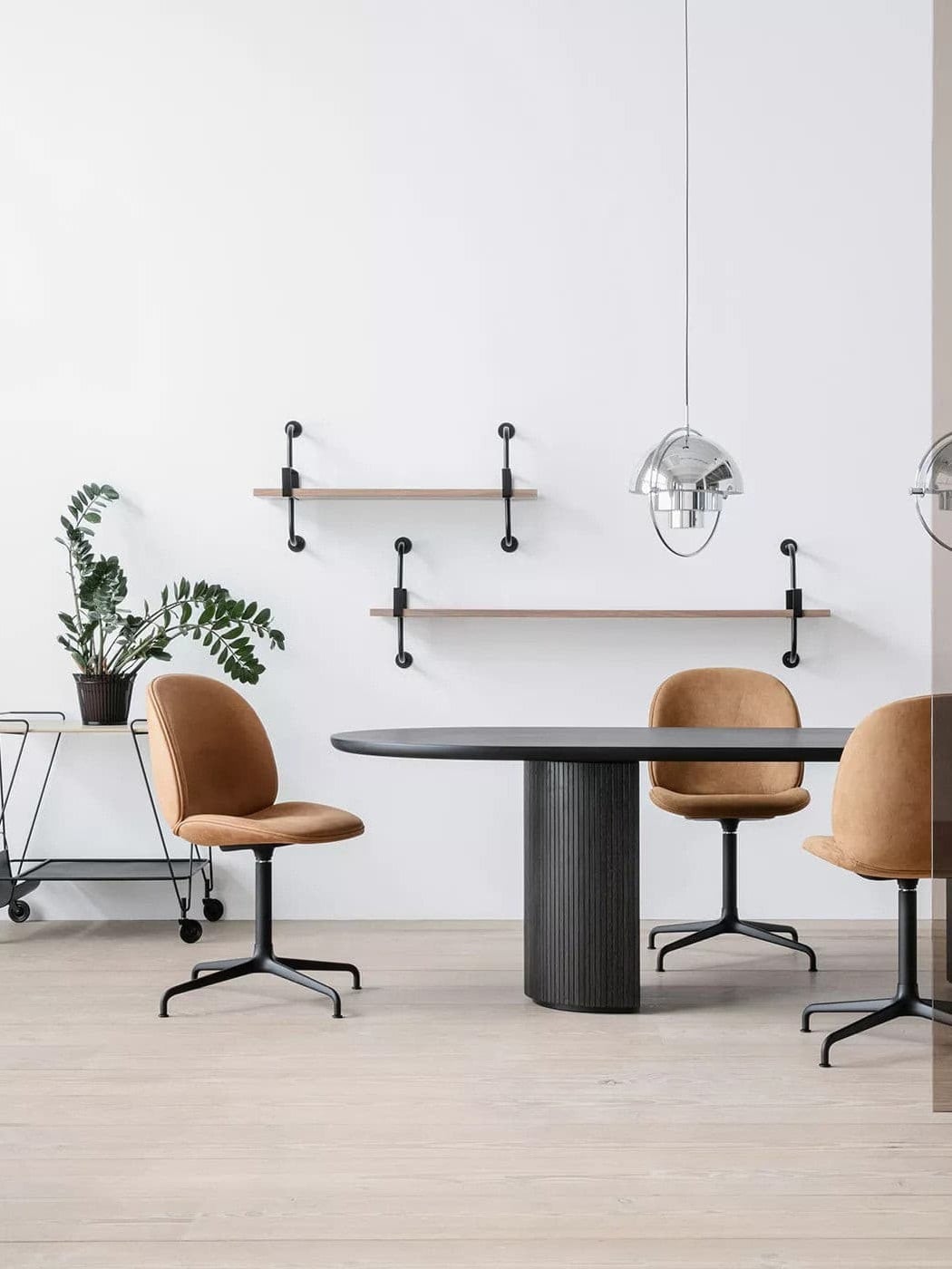 Chrome-finish pendants above a dark meeting table with tan chairs